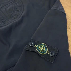 Svart Stone Island sweatshirt M - Äkta svart sweatshirt från Stone Island i storlek M. Klassisk rund hals, ribbade muddar och ikonisk patch på vänster ärm. Mjuk bomullskvalitet och diskret broderad logga på bröstet. Perfekt för dig som gillar streetwear och stilren design. Pris kan diskuteras!