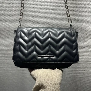 Svart axelväska med kedja - Snygg svart axelväska från pull&bear med silverfärgad kedja som axelrem. Perfekt storlek för mobilen och det viktigaste.❤️❤️