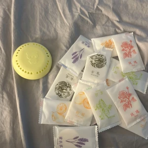 Doftspridare - Bilden visar ett set med små doftpåsar i olika dofter, samt en rund gul behållare med björnmotiv. 15 dofter, kliserlappen på hållaren är borta men går att lägga ned eller sätta dit ny