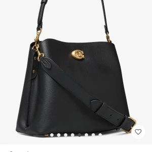 Svart axelväska från Coach i skinn - Stilren svart axelväska från Coach i mjukt, kornigt skinn med guldfärgade metalldetaljer och klassiskt vridlås framtill. Väskan har justerbar axelrem och extra rem för crossbody, perfekt för dig som gillar en clean och lyxig look.