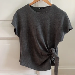 Grå topp med knyt från Zara - Säljer denna jättefina gråa topp med knyt från zara! Jag har använt den väldigt mycket men den har inga slitningar❤️