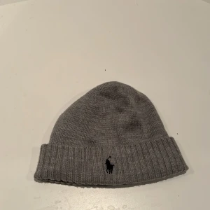 Grå ullmössa från Polo Ralph Lauren - Snygg grå mössa från Polo Ralph Lauren i 100% ull. Använd ca 2-3 gånger jättebra skick och verkligen jätteskön.