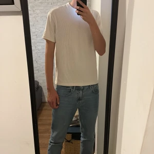 Beige ribbad t-shirt från FSBN - Säljer en stilren beige t-shirt från FSBN i storlek M. T-shirten har ribbad struktur, rund hals och korta ärmar. Perfekt för dig som gillar enkel och clean look. Materialet är mjukt och skönt, troligtvis bomull. Passformen är normal.