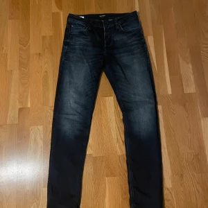 Mörkblå Jack&Jones jeans 30/34 - Snygga mörkblå jeans från Comfort/Mike i storlek 30/34. Jeansen har en klassisk femficksdesign, raka ben och diskreta slitningar för en cool look. Perfekta för dig som gillar en bekväm passform och stilren design.