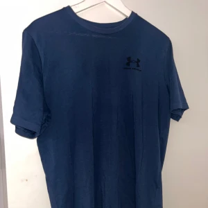 Blå Under Armour t-shirt loose fit - Snygg marinblå t-shirt från Under Armour i loose fit. Klassisk rund halsringning och diskret logga på bröstet. Tillverkad i mjuk bomullsmix som känns skön mot huden. Perfekt för träning eller chill dagar.
