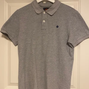 Morris piké S - Snygg grå pikétröja från Morris med klassisk krage och två knappar framtill. Tröjan har korta ärmar och en liten broderad logga på bröstet. Perfekt för en stilren och avslappnad look. Den kar krymt lite i tvätten och är snarare storlek S 