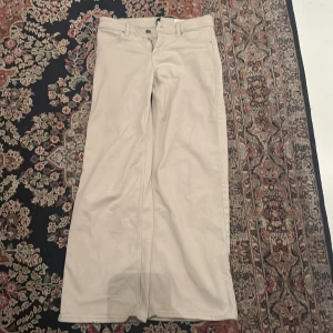 Beiga jeans - Snygga beiga byxor i rak modell med klassiska fickor både fram och bak. Byxorna har hällor för bälte och är tillverkade i mjuk bomull. Perfekta för dig som gillar en clean och enkel stil. Passar dig som vill ha ett par ljusa byxor med normal passform.