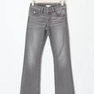 Grå bootcut jeans med fickdetaljer - Snygga grå jeans med bootcut passform och coola fickor med lock och knapp bak. Jeansen har klassisk femficksdesign, bälteshällor och dragkedjegylf. Perfekta för dig som gillar en avslappnad men trendig look.