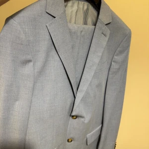 Stålblå extra slim Kostym - Dressmann - Snygg stålblå kavaj tillsamans med kostym byxor från Dressmann i extra slim fit. Kostymen har använts under bara ett tillfälle, sedan dess har den bara legat i garderoben. Perfekt för dig som gillar en modern och smal siluett. Jag är 172cm lång och jag väger ungefär 72-74 kg. Den sitter perfekt på mig. 