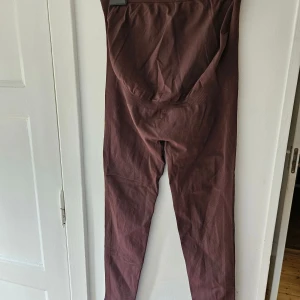 Bruna gravidtights - Säljer ett par bruna  gravid leggings tight passform. Materialet är mjukt och stretchigt, perfekt för att ge en skön känsla hela dagen. Snyggt ribbade detaljer längs sidorna och sömlös design för en clean look.