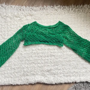 Grön shrug/bolero - Egentillverkad stickad bolero/shrug i fin grön färg! Passar perfekt både på vintern och sommaren. Armlängd (armhåla - kant): ca 48 cm. Höjd: ca 20 cm. Skulle säga ca stl S/M.