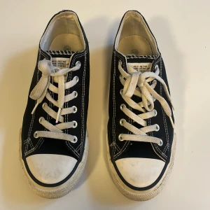 Svarta låga sneakers med vit sula - Klassiska svarta sneakers från 157 med vit gummisula och tå, vita snören och kontrasterande vita sömmar. Modellen är låg och har rund tå. Perfekta för en avslappnad och stilren look.