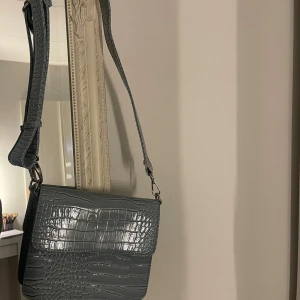 HVISK väska  -  axelväska med bred justerbar rem och krokopräglat mönster.  Väldigt praktiskt och smidigt. Nypris: 599