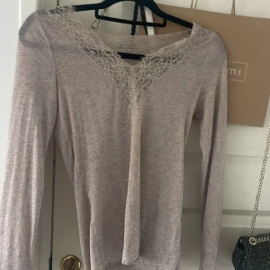 Beige långärmad topp med spets från Intimissimi - Supersnygg beige långärmad topp från Intimissimi i mjuk kashmirblandning. V-ringad med vacker spetsdetalj vid halsen 