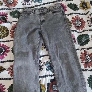 Grå tvättade jeans loose fit  - Snygga grå jeans med tvättad look och raka ben. Klassisk femficksmodell med bälteshällor och dragkedja. Jeansen har en avslappnad passform och passar perfekt till en streetinspirerad stil.