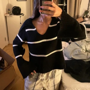 Svartvit randig stickad tröja - Säljer en svart stickad tröja med vita horisontella ränder. Tröjan har v-ringning och vida, långa ärmar som ger en avslappnad look. Perfekt för dig som gillar en lite oversized och mysig stil. Köpte den här på plick för ett tag sen men har endast använt den en gång. Bilden är från tidigare ägaren☺️