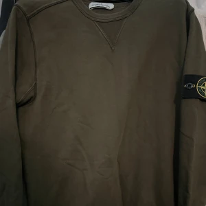 Olivgrön Stone Island sweatshirt S - Säljer en olivgrön sweatshirt från Stone Island i storlek S. Tröjan har klassisk rund halsringning, ribbade muddar och den ikoniska Stone Island-patchen på vänster ärm. Tröjan är använd ett tiotal gånger vilket innebär att den är i väldigt bra skick. 