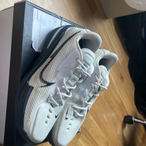 Nike Air G.T. Cut 1 - Säljer mina Nike Air Zoom G.T. Cut TBP sneakers i vitt med svarta detaljer. Perfekta inomhusskor gjorda för basket i storlek 46. Sköna och passar dig som springer snabbt och hoppar mycket. Sällsynta och svåra att få tag på. Skriv gärna om ni har andra frågor!