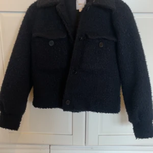 Svart teddyjacka med fickor - Mysig marinblå  teddyjacka med krage och två stora bröstfickor med knappar. St 170 från Gina.