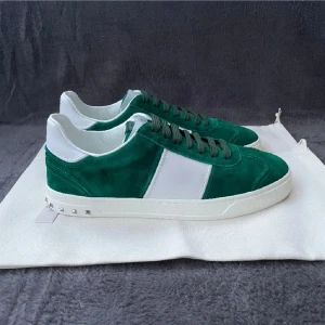 Valentino Garavani gröna sneakers - Snygga gröna och vita sneakers från Valentino Garavani med mockadetaljer och vita skinnpartier. Skorna har en bred vit rand på sidan, gröna snören och coola nitar längs hälen. Perfekt för dig som vill sticka ut med stilrena och lyxiga sneakers.