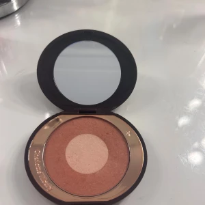 Charlotte Tilbury Pillow Talk Rouge - Charlotte Tilbury Cheek to Chic i nyansen Pillow Talk. Fint puderrouge med två toner: en varm rosabrun yttre cirkel och en ljusare skimrig mitt. Kommer i en rund, brun och guldig dosa med spegel. Perfekt för att ge kinderna en naturlig glow.