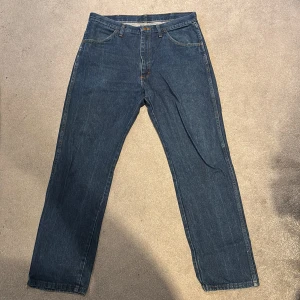 Rustler Jeans 36/32 - Jeans i mörkblå denim med raka ben och femficksmodell. Byxorna har normal/straight form bälteshällor och knappgylf. Perfekta för en avslappnad och tidlös look.