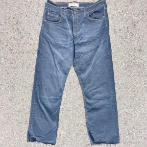 Blå jeans från Wrangler med rå kant - Säljer ett par klassiska blå jeans från Wrangler med raka ben och rå, avklippt kant nertill. Dessa byxor är inte använda då storleken inte passar mig pris går och diskuteras     STORLEK 31 : 32