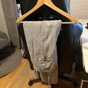 Grå linnebyxor med snörning från Selected homme - Snygga grå linnebyxor med avslappnad passform och snörning i midjan. Byxorna har en bakficka med knapp och en liten etikett. Perfekta för en chill och stilren look.
