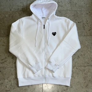 Vit zip från Cdg Play - Säljer denna vita zip-tröjan från Cdg play i storlek M, sjukt mjuk på insidan och logga fram med tryck på ryggen. 10/10 skick och fraktar inom 24h✅