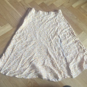 Gulblommig kjol från SHEIN XS - Supersöt gul kjol från SHEIN i storlek XS med vitt blommönster. Kjolen är lång, har en lätt utställd form och stängs med en gul dragkedja i sidan. Perfekt för dig som gillar ljusa och somriga vibes!