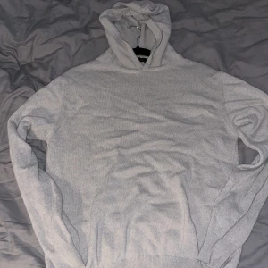 Ljusgrå hoodie/ beige från Oscar Jacobson - Säljer en stilren ljusgrå hoodie från Oscar Jacobson i merino och Kashmir blandning. Tröjan har huva, långa ärmar och ribbade muddar. Perfekt för dig som gillar en clean och enkel look med premiumkänsla. Har en liten fläck men den går säkert bort efter någon tvätt.
