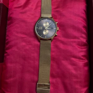 Jernhest guldig meshklocka - Stilren klocka från Jernhest med guldig mesh-länk och mörkblå urtavla. Klockan har två mindre urtavlor, datumvisning och snygga detaljer i guld. Boetten är i rostfritt stål och armbandet är justerbart för perfekt passform. Batteriet är tyvär slut. Ny pris ligger runt 1000-1500 inte helt säker så priset är väldigt bra men går att diskutera.