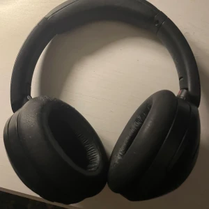 Sony WH-1000XM4 hörlurar - Sony WH-1000XM4 trådlösa over-ear hörlurar med aktiv brusreducering. Svart färg, bekväma öronkuddar och justerbar bygel. Mindre tecken på användning men i gott skick. Perfekt för musik, resor och arbete tack vare lång batteritid och hög ljudkvalitet.