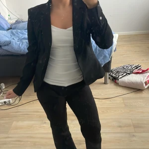 Svart kavaj från H&M, storlek 38 - Säljer en svart kavaj från H&M i storlek 38. Kavajen har klassisk passform med en knapp framtill, smala slag och två fickor. Fodrad insida i grått tyg. Perfekt för en clean och stilren look.