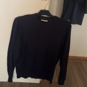 Svart stickad tröja från Zara - En stilren svart stickad tröja från Zara i storlek S. Tröjan har rund halsringning och långa ärmar, perfekt för dig som gillar enkel och clean look. Materialet är mjukt och skönt, passar till många olika outfits. Snygg att bära både till jeans och kjol.