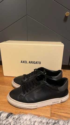 Svarta sneakers från Axel Arigato - Snygga svarta sneakers från Axel Arigato med vit platt sula och diskret logga på sidan.  OBS PRIS KAN DISKUTERAS