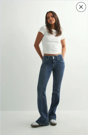 Blå bootcut jeans från Nelly, EU 40 - Snygga blå bootcut jeans från Nelly i storlek EU 40. Low waist modell med broderade detaljer på backfickorna. Säljs för 699 kr på Nellys sida. Säljer då de är för korta för mig som är 174 cm!