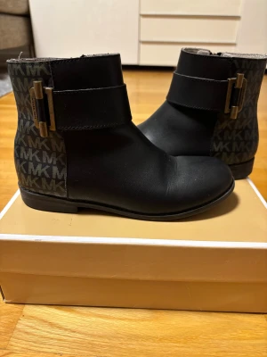 Svarta boots från Michael Kors storlek 33 - Två olika dragkedjor på skorna då den ena gick sönder (se bild 5). Snygga svarta boots från Michael Kors med MK-logga i mönster på hälen och sidorna. Storlek 33. 