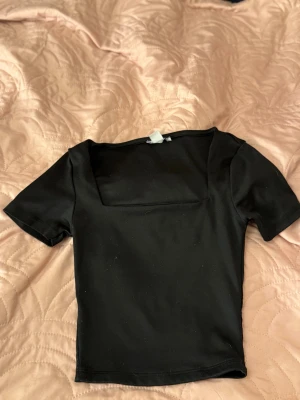 Svart croppad topp  - Säljer en svart croppad topp med korta ärmar och en snygg fyrkantig halsringning. 