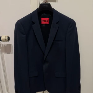 Hugos boss kavaj - Säljer min mörkblå kavaj från Boss som enbart är använt vid enstaka tillfällen och är därför i jättebra skick. Nypris på denna är 3500 kr.