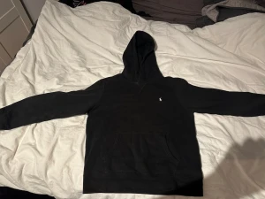 Svart Ralph Lauren Hoddie - Säljer denna svarta Ralph Lauren hoodie då den blivit allt för liten och jag behöver pengar😭🤑pris går självklart att diskuteras och det är bara fråga om du har någon fundering eller fråga!!!😊