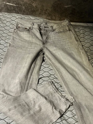 Grå jeans från Gina tricot, storlek 34 - Säljer ett par grå jeans från Perfect Jeans i storlek 34. Klassisk femficksmodell med bälteshällor och knappstängning. Jeansen har en rak passform och är tillverkade i slitstarkt bomullsmaterial. Perfekt för dig som gillar en enkel och clean look.