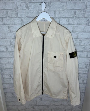 Stone Island jacka - Stone Island overshirt i ljus beige färg med klassisk patch på armen. Stilren och tidlös modell som passar perfekt till vardag och vår/sommar. Sparsamt använd och i toppskick. Autentisk med certilogo. Hör av dig vid intresse 🙌