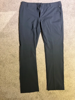 Mörkblå byxor från Abacus W36/L32 - Snygga mörkblå byxor från Abacus i storlek W36/L32. De har klassisk rak passform, bälteshällor och sidofickor. Materialet är mjukt och lätt, perfekt till golfrundorna. 