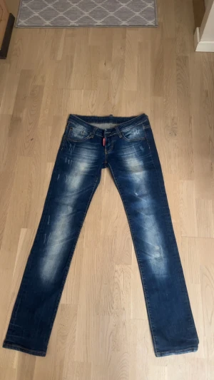 Dsq2 äkta såklart  - Snygga blå jeans från Dsquared2 med coola slitningar och tvättade detaljer. På bakfickan finns ett broderat rött lönnlöv med Dsquared2-logga. Klassisk femficksmodell och rak passform. Perfekt för dig som vill sticka ut med en unik detalj.