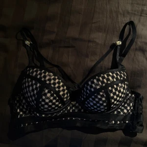 Svart nätmönstrad bh - Snygg svart bh med vadderade kupor och nätmönster i beige och svart. Justerbara axelband och hakknäppning bak. Snygga detaljer med genomskinliga partier och kontrasterande sömmar🖤använd fåtal gånger!!