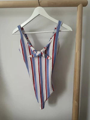 Randig linnebody från Bershka - Säljer en snygg randig linnebody från Bershka i storlek S. Toppen har breda axelband, knytning i ryggen och är tillverkad i mjuk bomull. Färgerna är vit, blå och röd, med ett fräscht och somrigt vibe. Helt ny.