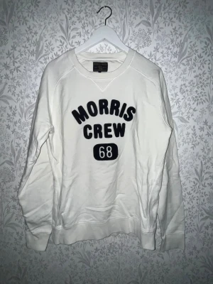Morris Gents tröja  - Säljer en vit sweatshirt från Morris Gents. Tröjan har svart text 'Morris Crew 68' framtill och är långärmad med rund hals. Materialet är mjuk bomull och passformen är normal. Längd 71cm. JAG SKICKAR EJ FLER BILDER NÄR JAG BÄR JEANSEN! för storleksguide hänvisar jag till måtten och för bättre inblick i passformen rekommenderar jag att googla på modellnamnet. kolla måtten noggrant :) !!
