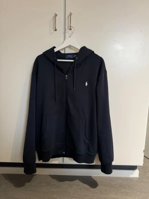 Marinblå zip hoodie Ralph Lauren - Säljer denna snygga marinblåa zip hoodie från Ralph Lauren. Passar perfekt till alla lägen och årstider! Tveka inte att höra av dig vid intresse