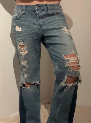 Blå ripped jeans med straight fit - Säljer ett par blå jeans med flera stora slitningar och hål på både fram- och baksida av benen. S/M Midjemått rakt över: 42 cm Innerbenslängd: 66 cm